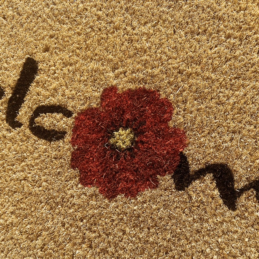 Nachhaltige Fußputzmatte aus Kokos dekoriert mit Blume in rot